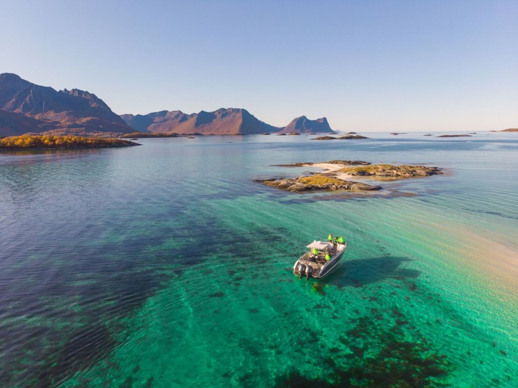 En båt i ett blågrönt hav utanför Senja i Norge